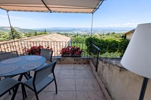 a patio with a table and chairs on a balcony at Le Clos Du Buis in Bonnieux