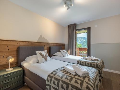 deux lits dans une chambre d'hôtel avec une fenêtre dans l'établissement Apt Alchimie B11 - Châtel BO Immobilier, à Châtel