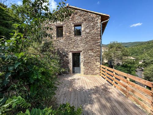 une maison en pierre avec une passerelle en bois devant elle dans l'établissement La Clède de Monte-Rotundo, à Saint-Romans-de Codière