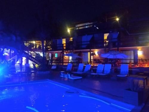 a swimming pool with chairs and umbrellas at night at Pousada Vila do Sol in Búzios