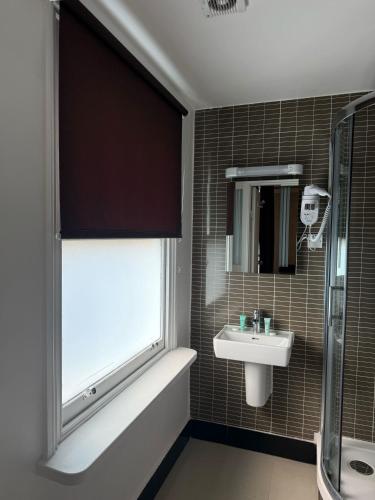 a bathroom with a sink and a window and a tub at Hyde Park Suites in London