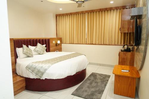 a bedroom with a bed and a flat screen tv at Hotel Bhagyalaxmi Luxury Inn in Ahmedabad
