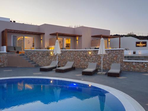 a villa with a swimming pool in front of a house at Moonlight Apartments & Suites in Fira