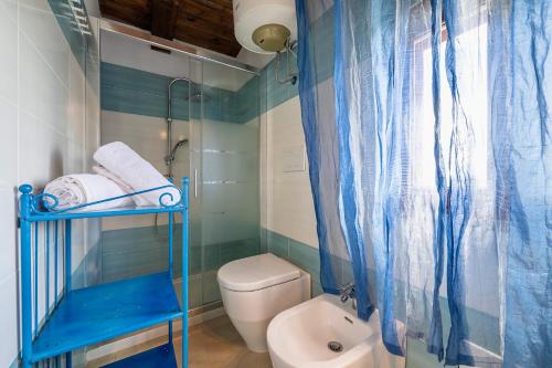 a bathroom with a toilet and a blue shower curtain at Villa in Alghero just 5 minutes from the historical center in Casa Linari