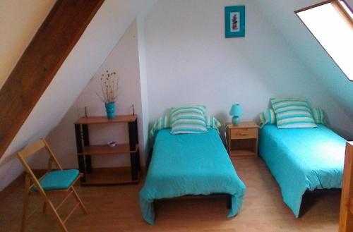 une chambre mansardée avec deux lits et une fenêtre dans l'établissement Gîte le Lasnier, à Crasville