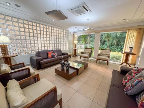 a living room with couches and chairs and a table at Hotel Nacional Inn Guarujá in Guarujá
