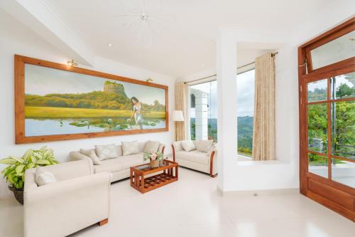 a living room with white furniture and a large painting on the wall at Rose Hill Bungalow in Gampola