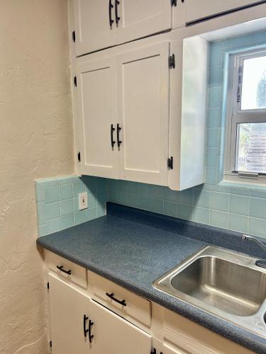 a kitchen with white cabinets and a sink at Historic Home near the water - perfectly walkable spot! in Lake Worth