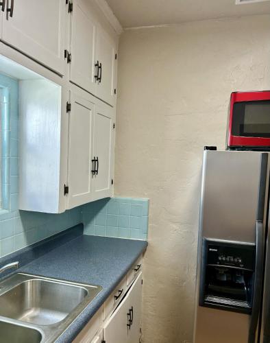 a kitchen with white cabinets and a sink and a refrigerator at Historic Home near the water - perfectly walkable spot! in Lake Worth