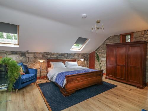 a bedroom with a bed and a blue chair at Woodville Lodge in Ród