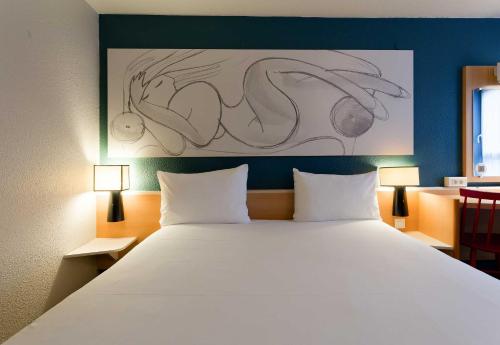 a bedroom with a large bed with two lamps at B&B HOTEL Reims Centre Erlon in Reims