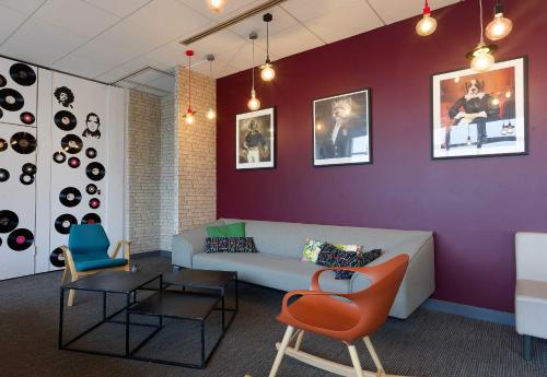 a living room with a couch and a table and chairs at B&B HOTEL Reims Centre Erlon in Reims