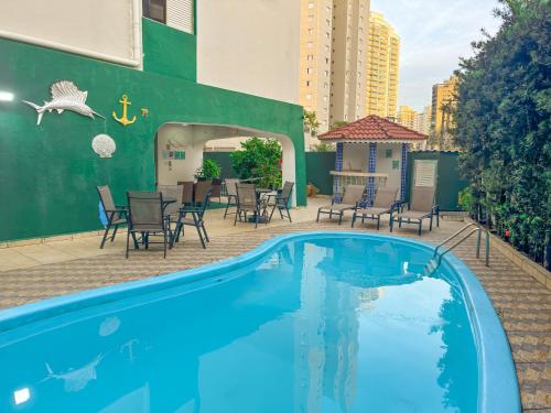 a blue swimming pool with chairs and a table at Hotel Nacional Inn Guarujá in Guarujá