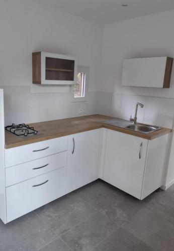 una cocina con armarios blancos y un fregadero en Charmante maisonette, en Porto Vecchio