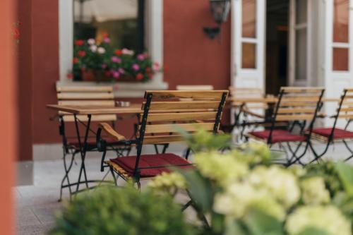 a row of wooden chairs and tables with flowers at Hotel Bären in Feldkirch