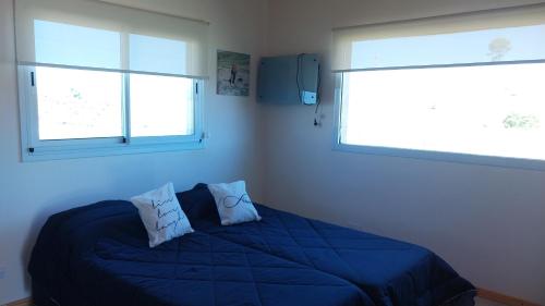 ein Schlafzimmer mit einem blauen Bett mit zwei Fenstern in der Unterkunft La agreste in Villa Yacanto