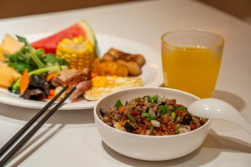 a table with a bowl of food and a glass of orange juice at Wenzhou Wuma Street Wenyuan Hotel is located in the heart of the city, easy to travel, free WiFi, breakfast, coffee, afternoon tea, free laundry service, recommended tourist attractions in Wenzhou