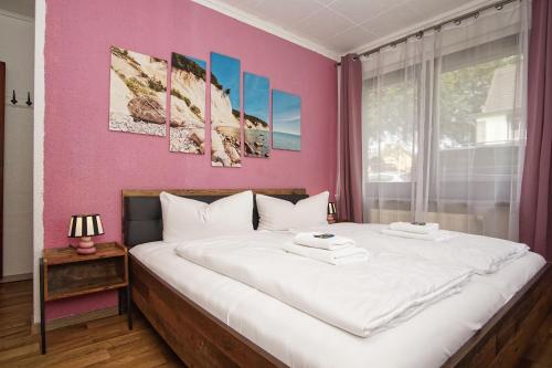 a bedroom with a large bed with a pink wall at Ferienhus Baabe FeWo 02 Terrasse, gratis Nutzung vom AHOI Erlebnisbad und Sauna in Sellin in Baabe