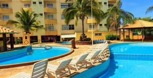 a resort pool with lounge chairs and a hotel at Thermas Place Suítes Caldas Novas temporada in Caldas Novas