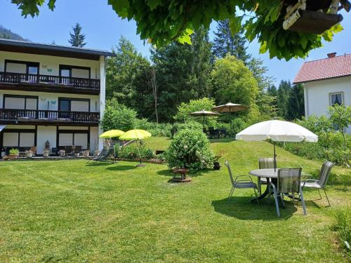 a table and chairs with umbrellas in a yard at Pension & Apartments Weissbriach in Weissbriach