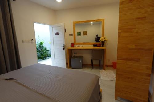 a bedroom with a bed and a desk and a mirror at Stay Kora in Thinadhoo