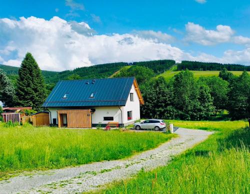 a house with a car parked next to a gravel road at Apartmán Matylda in Deštné v Orlických horách
