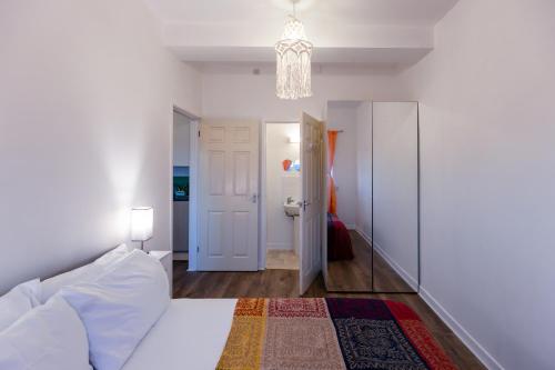 a white bedroom with a bed and a chandelier at Glastonbury!-CountrysideViews-Sleeps2 in Glastonbury