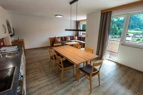 a kitchen and living room with a wooden table and chairs at Appartements MaLo by we rent in Viehhofen