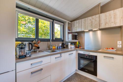 a kitchen with white cabinets and a sink at Chalet de la Grenatière in Pomérols