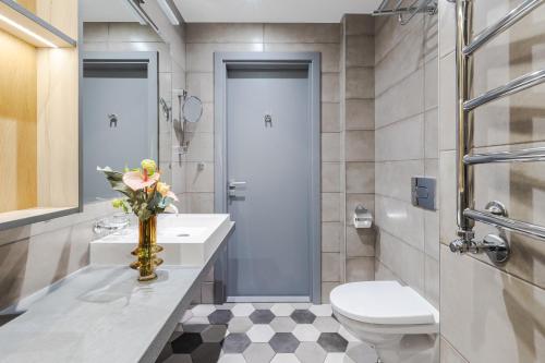 a bathroom with a toilet and a vase of flowers on a counter at Eurostars Metropole in Rīga