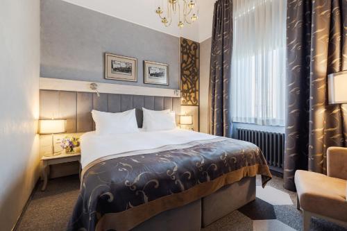 a hotel room with a bed and a chair at Eurostars Metropole in Rīga