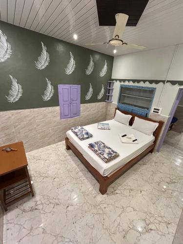 ein Schlafzimmer mit einem Bett mit weißen Federn an der Wand in der Unterkunft TEMPLE VIEW GUEST HOUSE in Hampi