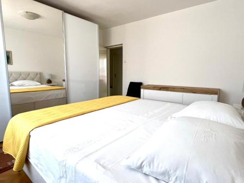 a bedroom with a large white bed and a mirror at Apartment Vito in Postira