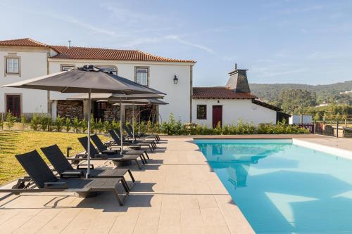 a pool with chairs and an umbrella next to a house at CasaNova Farmhouse in Braga