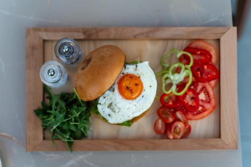 a wooden tray with a sandwich with an egg and vegetables at Haven Luxury Living in Chaïdeftón