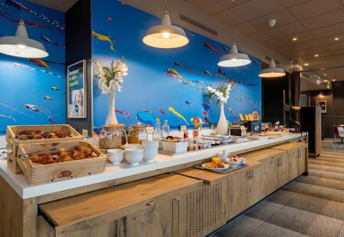 un buffet avec de la nourriture sur un mur bleu dans l'établissement B&B HOTEL Boulogne-sur-Mer Centre Les Ports, à Boulogne-sur-Mer
