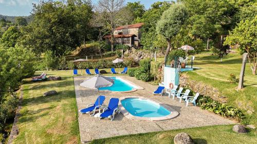 an outdoor swimming pool with chairs and an umbrella at Quinta da Chanca in Paredes de Coura