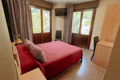 a bedroom with a red bed with a red blanket at Hotel Anna in Cocentaina