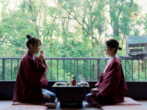 two women sitting next to each other in front of a window at LiVEMAX RESORT Okudogo in Matsuyama