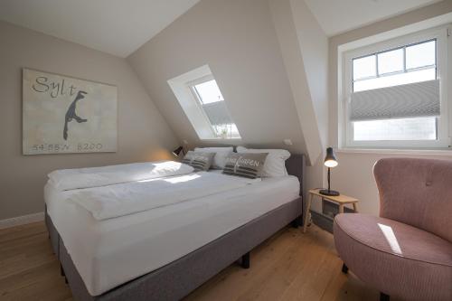 une chambre avec un grand lit blanc et une chaise dans l'établissement Möwennest, à Tinnum