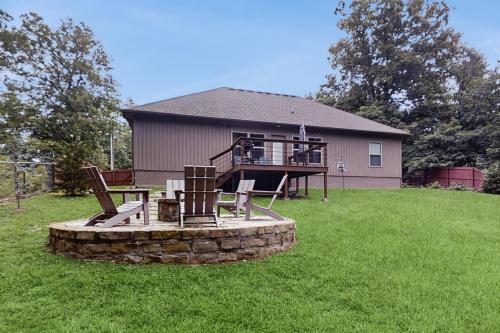 a house with a deck and chairs on a lawn at Serendipity in Bella Vista