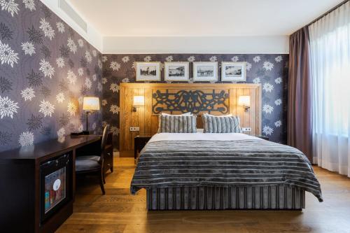 a bedroom with a bed and a desk and a television at Eurostars Metropole in Rīga