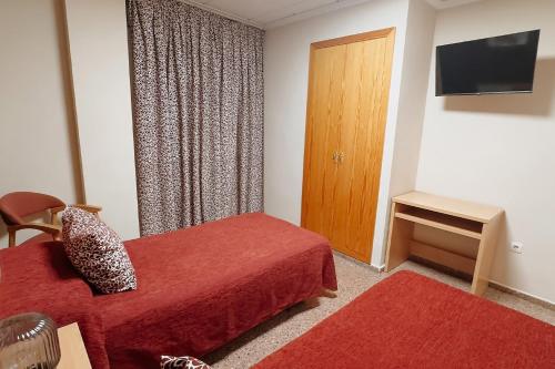 a hotel room with a red bed and a television at Hotel Anna in Cocentaina
