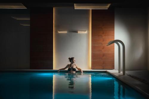 una mujer sentada en una piscina en Hotel Ambasciatori, en Riccione