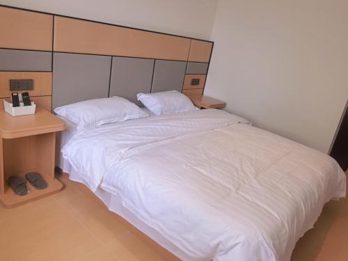 a bedroom with a large white bed and a night stand at Yushe Shiguang Xiaozhu in Jining
