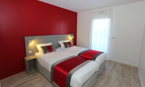 une chambre avec un grand lit avec un mur rouge dans l'établissement Les Criquets Hôtel & Spa, à Blanquefort