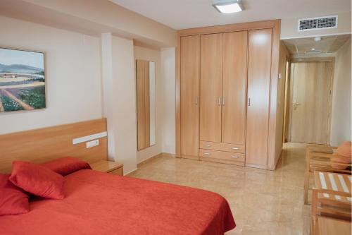 a bedroom with a red bed and a wooden cabinet at Hotel Anna in Cocentaina