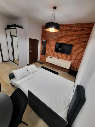 - une chambre avec un grand lit blanc et un mur en briques dans l'établissement Apartament Jagiellońska, à Bydgoszcz