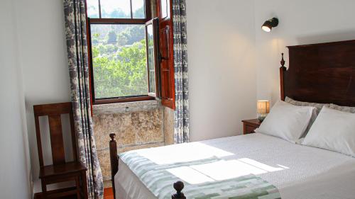Un dormitorio con una cama grande y una ventana. en Quinta da Chanca, en Paredes de Coura