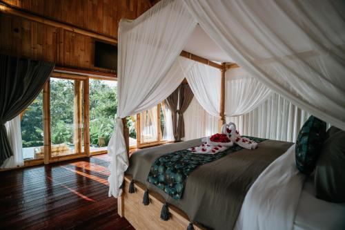 a bedroom with a canopy bed with pillows on it at Umah Bali Kuno Villa New in Tampaksiring